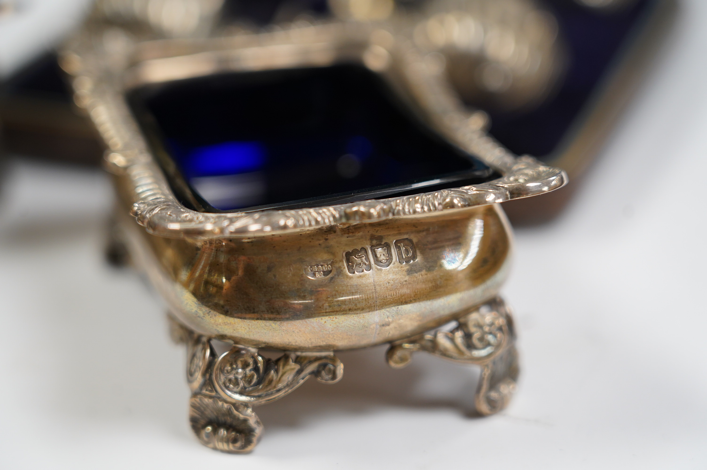 A pair of late Victorian silver rectangular salts, Hawksworth, Eyre & Co, London, 1897, 91mm with blue glass liners and a cased set of four Victorian silver tub salts with spoons. Condition - fair